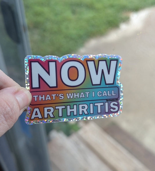 Colorful sticker with text held against a blurred outdoor background