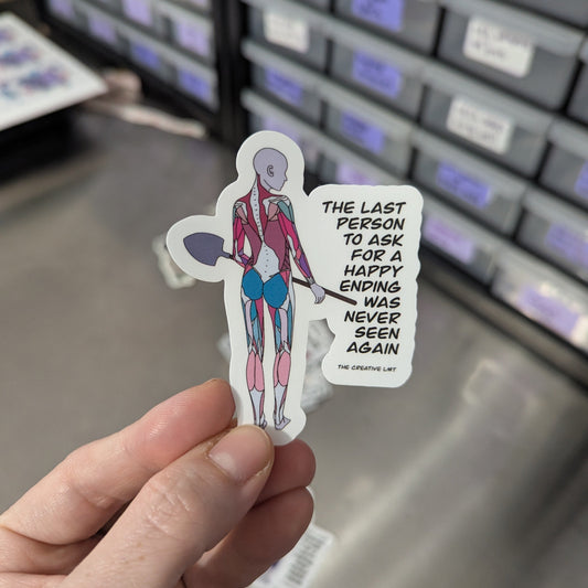 Hand holding a sticker with a character and text in front of labeled drawers.
