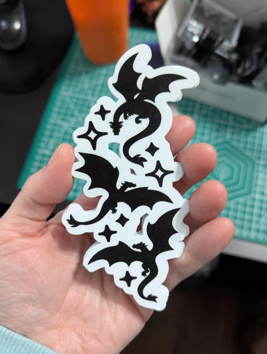 Hand holding a black and white dragon design against a blurred background
