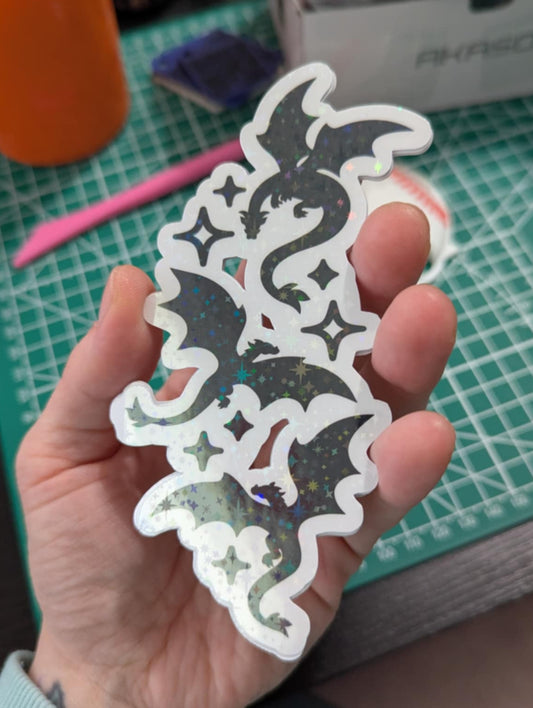 Hand holding a decorative cutout with intricate designs on a cutting mat.