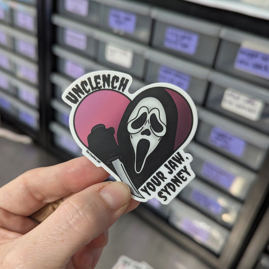 Hand holding a sticker with a graphic design in front of a storage unit.